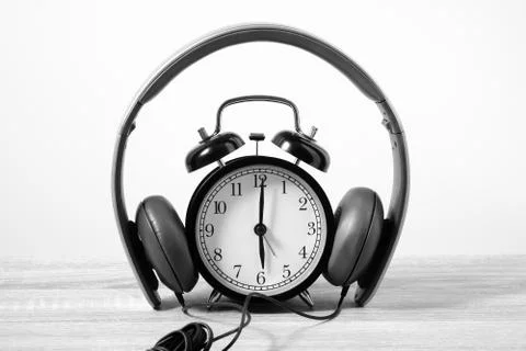 Front View Alarm Clock put on headphones over Wooden Table. Timeless Music .. Stock Photos