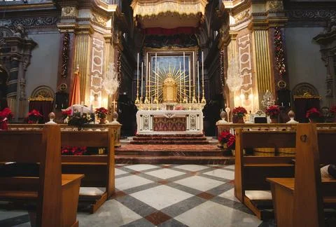 Front view of an altar in a large catholic church with wooden benches or pews Foto stock