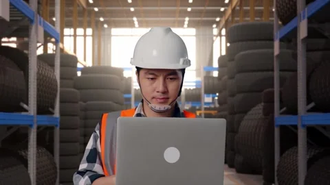 Front View of Asian Male Engineer Use Computer While Walking at Tire Warehouse Stock Footage 341784120