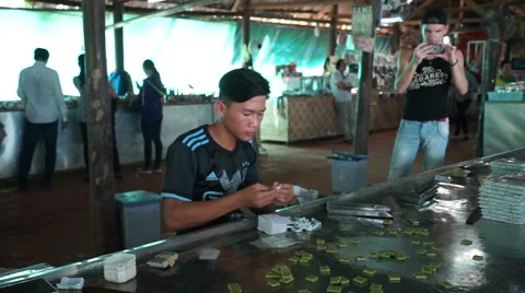 Front view as asian man is packing quickly coconut candies into a wrapper on the Stock Footage 67426103