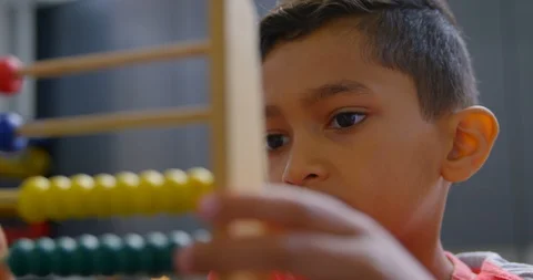 Front view of Asian schoolboy solving math problem with abacus at desk in a Stock Footage 106934993