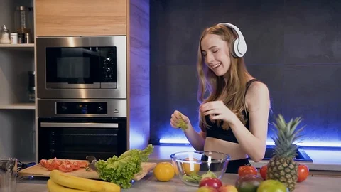 Front view of attractive smiling young woman in headphones which preparing fresh Stock Footage 127104047