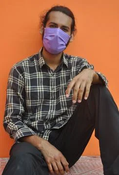 Front view of a attractive young man wearing protective face mask while sitting  Stock Photos