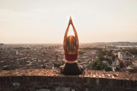 Front view of a back light of a faithful woman in yoga position holding the s Stock Photos