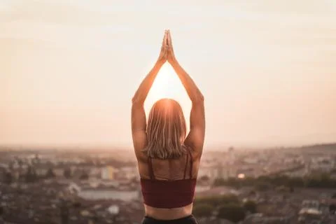 Front view of a back light of a faithful woman in yoga position holding the s Fotos Stock