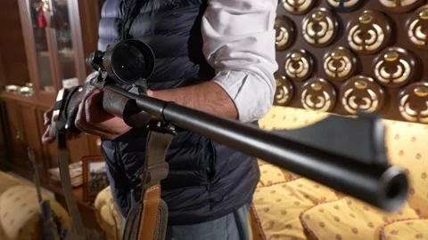 Front view of the barrel of a hunting rifle with a blurred hunter in the Stock Footage 329456066