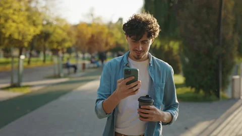 Front View of the Bearded Man Walking on the Street Using his Smartphone Stock Footage 238552669