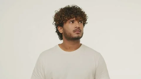 Front view of bewildered Indian man looking around. Studio footage of brunette Stock Footage 232470020