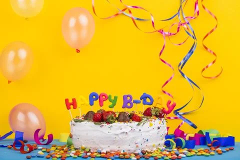 Front view birthday cake surrounded by party elements Stock Photos