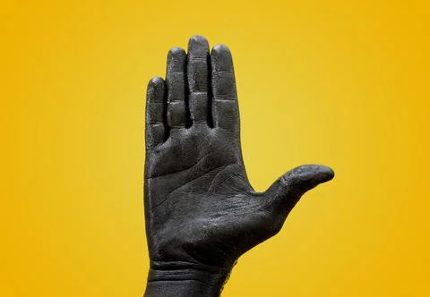 Front view of a black painted hand with yellow background Stock-Fotos