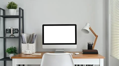 Front view of blank computer screen, lamp and supplies on wooden desk. Empty Foto stock