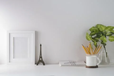 Front view blank picture frame, houseplant, pencil holder, book and coffee cu Stock Photos