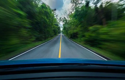 Front view of blue car driving with fast speed on the middle of asphalt roa.. Stock Photos
