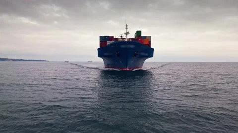 Front view of a blue container ship sailing through calm waters under a cloudy Stock Footage 300255142