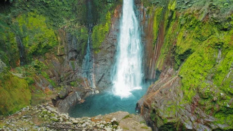 Front view of Blue Falls crashing into rocky pool with lush mossy canyon walls Stock Footage 319873055