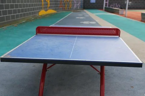 Front view of a blue outdoor table tennis table and red perforated net on a.. Stock Photos