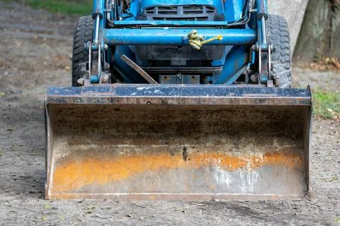 Front view of blue tractor loader metal bucket on ground. Stock Photos