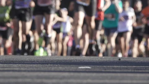 Front view of blurred runner legs running marathon with public voices Stock Footage