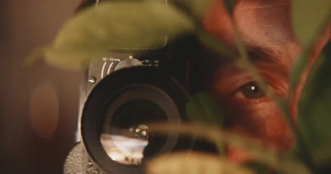 Front view of blurry plants with man in background taking pictures of plant Stock Footage 203576264