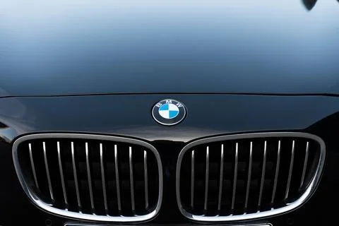 Front view of BMW logo on black car hood and chrome grille on bumper. High Stock Photos