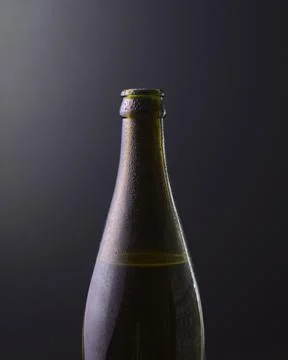 Front view of a bottle of cold beer with dark black background. Stock Photos