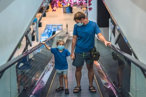 Front view boy, father going up escalator in super market wear face protect mask Stock Photos