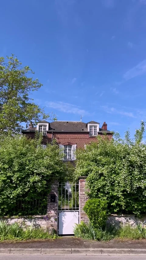 Front view of a brick country house in France, partially hidden behind dense Stock Footage 336035190