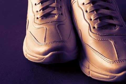 Front view of bronze colored chunky sole sneakers over dark purple background Stock Photos