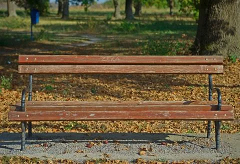 Front view on a brown bench on red bricks with nature behind it Stock Photos