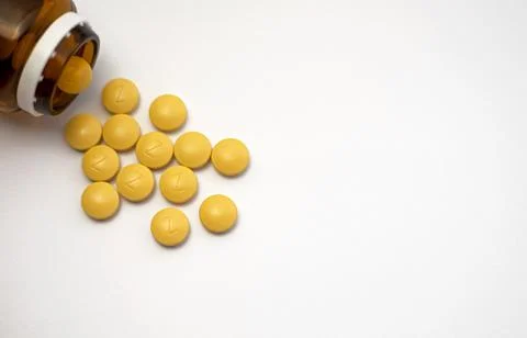 Front view of a brown bottle with several yellow iron tablets Stock Photos