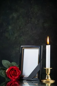 Front view of burning candle with red flower on black background evil death.. Stock Photos