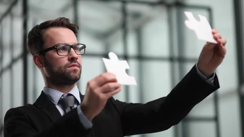 Front view of businessman holding two matching puzzle pieces Stock Footage 246320685