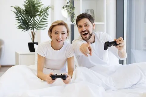 Front view of caucasian playing video games while sitting under blanket at home. Stock Photos