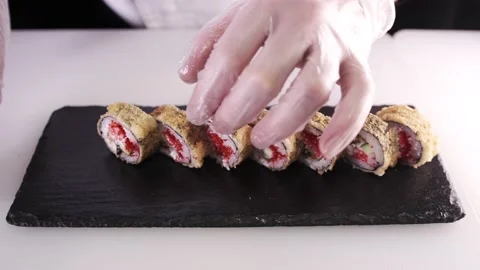 Front view of the chef hands in gloves laying japanese sushi rolls on a plate Stock Footage 133654717