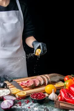 Front view chef squeezing lemon on fish slices knife on cutting board veget.. Stock Photos