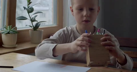 Front view of child kid choosing pencil for homework sitting by window natural Stock Footage 147036998