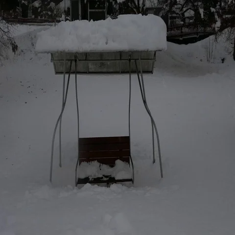 Front view of a children swing half way to the snow in a heavy snowy day Stock Footage 69558496