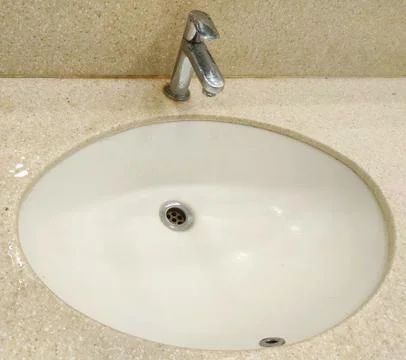 Front view of circular white bathroom sink on light cream marble with tap Stock Photos