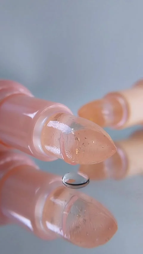 Front view of clear liquid dropping from above onto pink and yellow lip bal.. Stock Footage 340260686