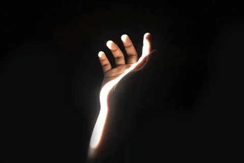 Front view close up of a human hand raised with a bright streak of light il.. Stock Photos