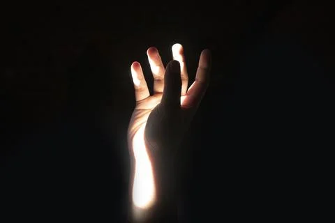 Front view close up of a human hand catching a narrow beam of dramatic high.. Stock Photos