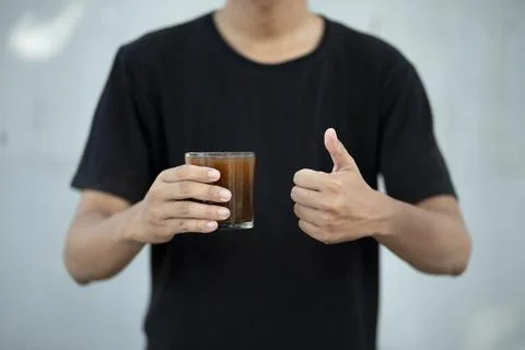 Front view close up of man hand holding coffee cup with thumbs up at home Foto stock