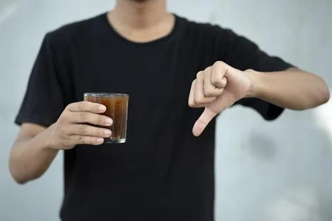 Front view close up of man hand holding coffee cup with thumbs down at home Foto stock
