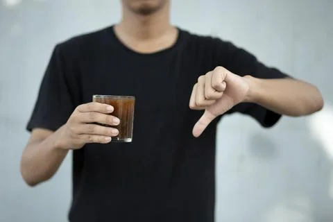 Front view close up of man hand holding coffee cup with thumbs down at home Stock Photos