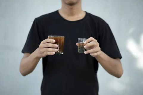 Front view close up of a man hands holding a coffee cup and liquid sugar at.. Foto stock