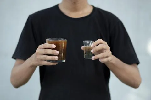 Front view close up of a man hands holding a coffee cup and liquid sugar at.. Stock Photos
