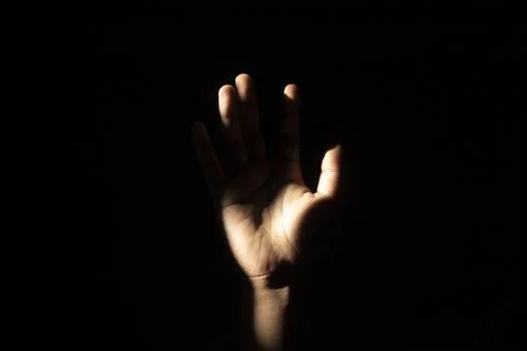 Front view close up of an open human hand raised under dramatic high-contra.. Stock Photos