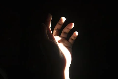 Front view close up of a slightly curled human hand illuminated by a dramat.. Stock Photos