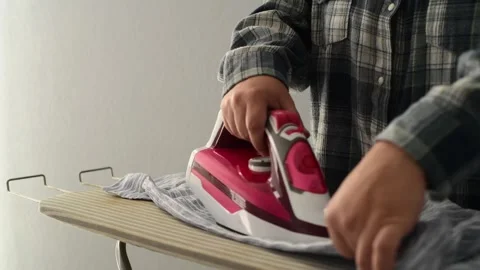 Front view close up of woman hands ironing clothes on an ironing board. 库存影片 328318949