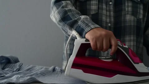 Front view close up of woman hands ironing clothes on an ironing board. Видео 328318950